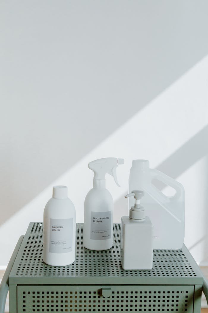 Minimalist photo of various white cleaning products arranged on a table.